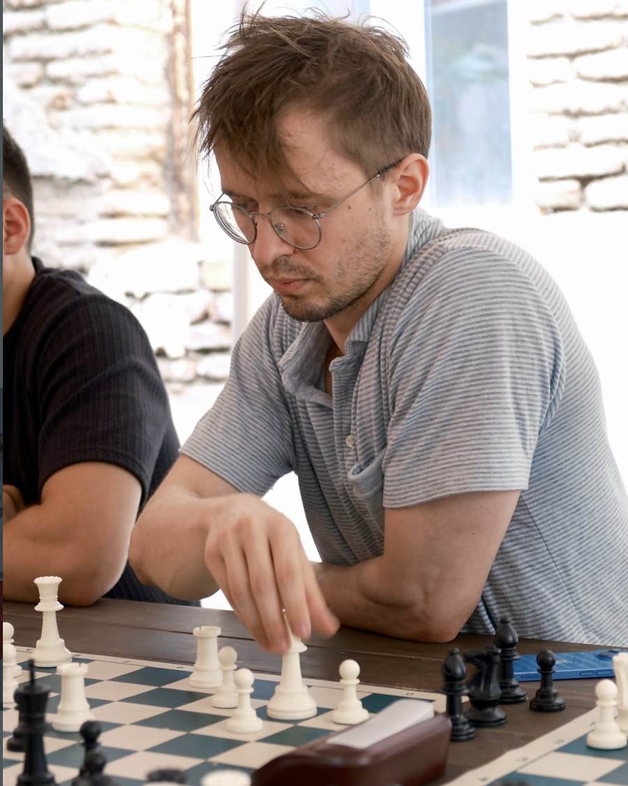 Igor Shatsev placing a white piece on the board mid-game, eyes on the position.