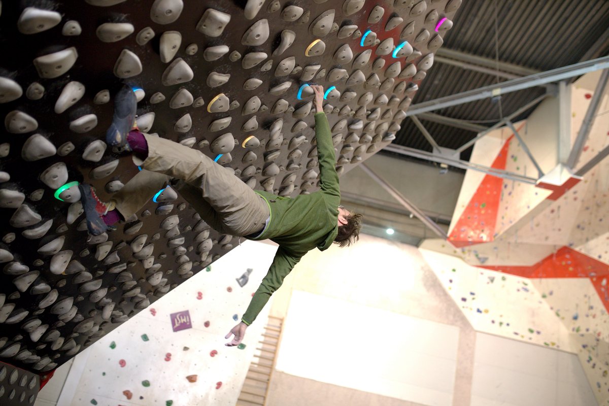 Igor Shatsev mid-move on a steep overhanging bouldering wall, shot from the floor.